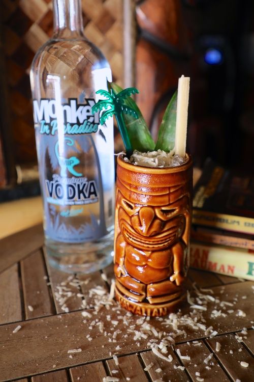 bottle of monkey in paradise vodka with a bang the tree cocktail in an authentic tiki mug