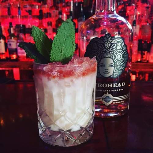 mermaids milk cocktail with a bottle of afrohead premium aged dark rum at tiki house key west