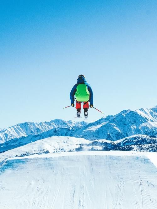 Skier Jumping In Air With Mountains Ahead.