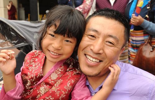 A man holding a young female child smiling.