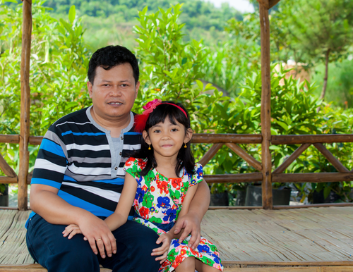 A man holding a young female child smiling.