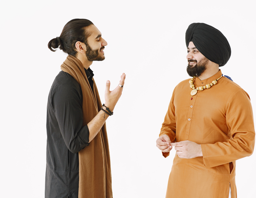 Four men standing and talking while smiling.